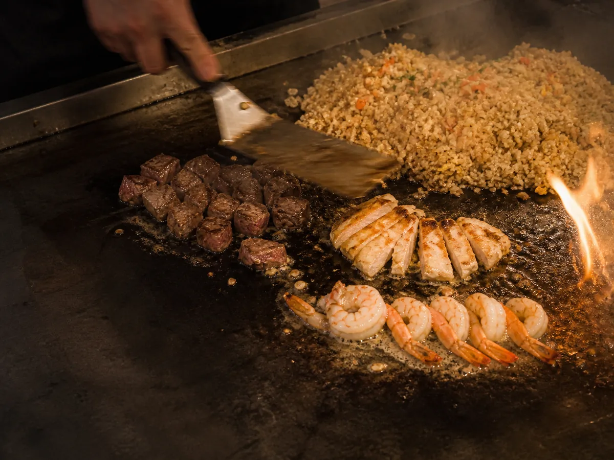 Steak, chicken, shrimp and fried rice cooking on the teppanyaki flat-top