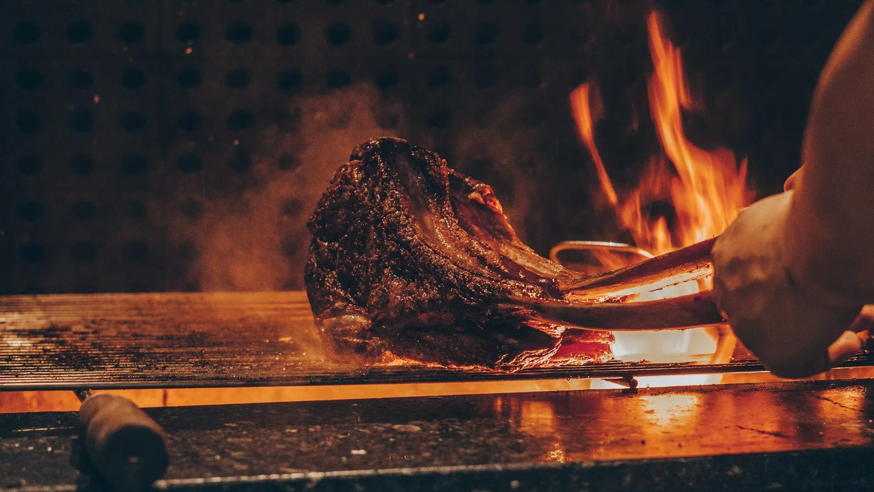 A thick cut of beef searing over an open flame