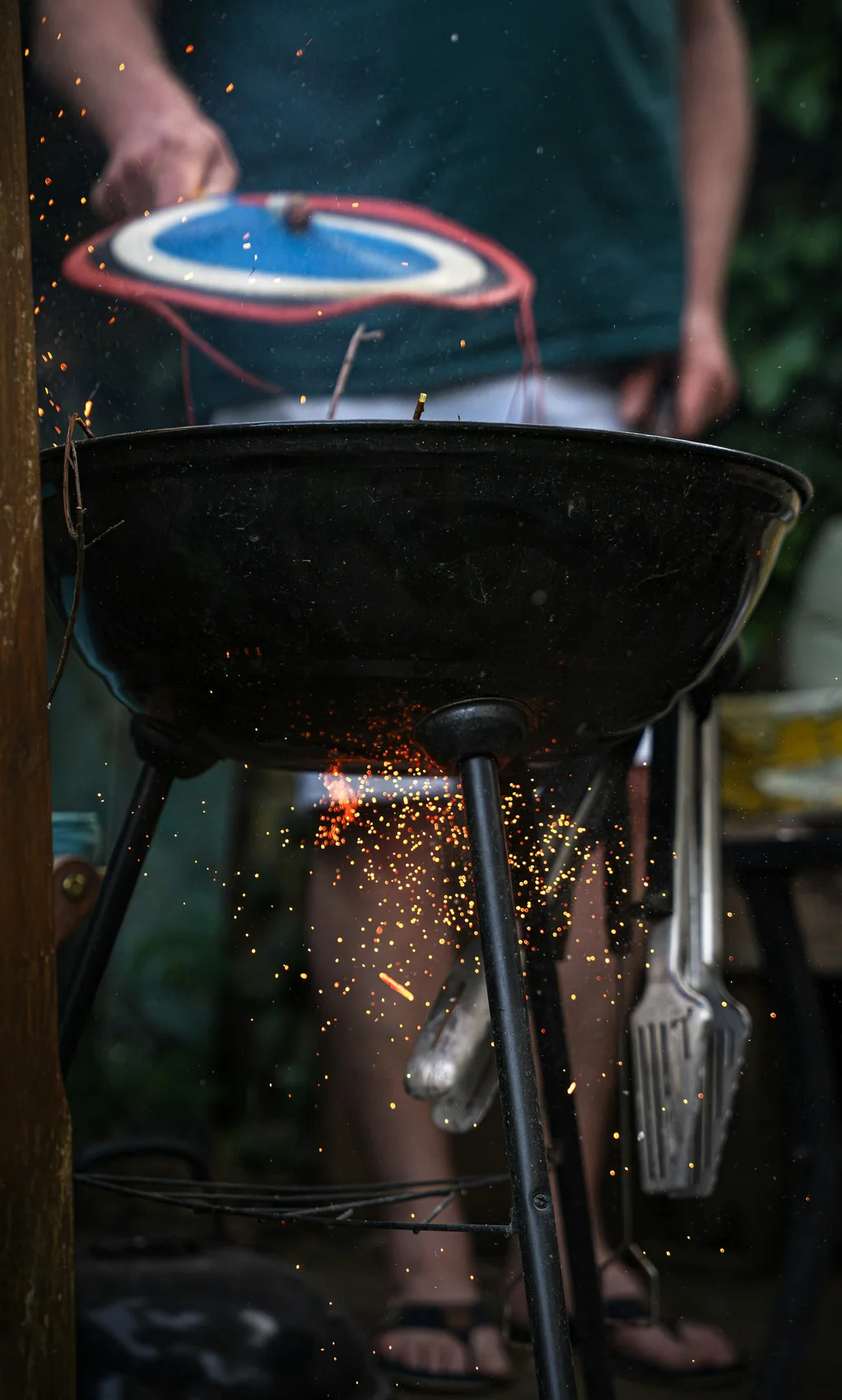 Sparks flying up from a charcoal grill being fanned in the dark