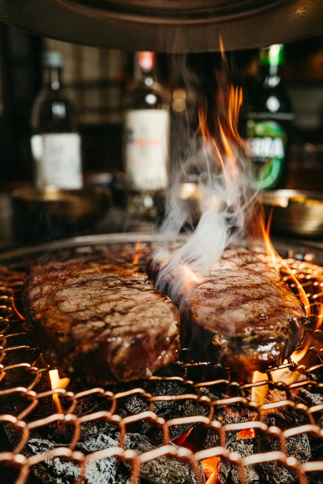 Two steaks searing over open coals on the hibachi grill
